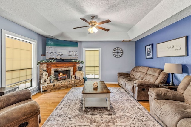 116 S Hackberry Ave, Luling, TX 78648 - living room with a raised ceiling, ceiling fan, wood finished floors, a textured ceiling, and a brick fireplace