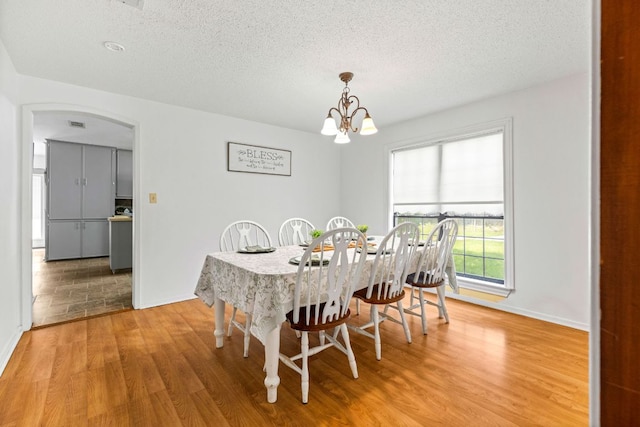 116 S Hackberry Ave, Luling, TX 78648 - dining room with light wood-style floors, a chandelier, baseboards, a textured ceiling, and arched walkways