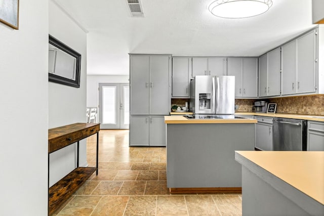 116 S Hackberry Ave, Luling, TX 78648 - kitchen with stainless steel appliances, gray cabinetry, tasteful backsplash, and light stone finish flooring