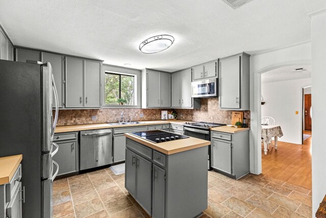 116 S Hackberry Ave, Luling, TX 78648 - kitchen with stainless steel appliances, gray cabinetry, a sink, arched walkways, and a textured ceiling