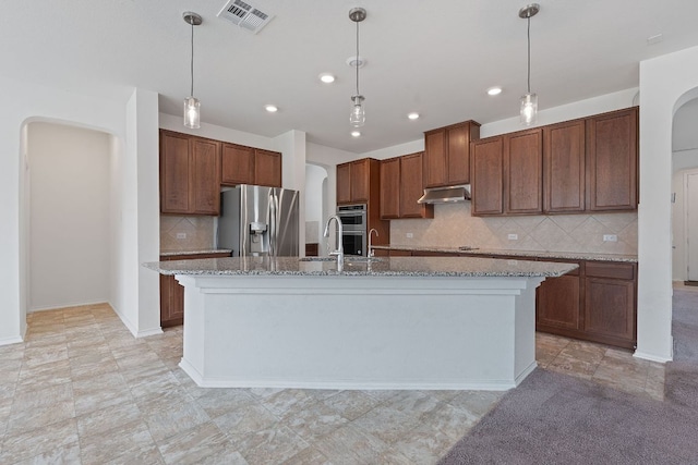 195 Azure Cv, Kyle, TX 78640 - kitchen with stainless steel appliances, arched walkways, under cabinet range hood, decorative backsplash, and an island with sink