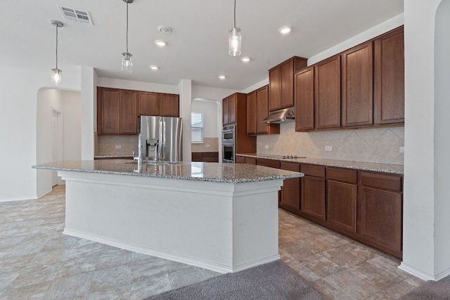 195 Azure Cv, Kyle, TX 78640 - kitchen with arched walkways, stainless steel appliances, under cabinet range hood, backsplash, and recessed lighting