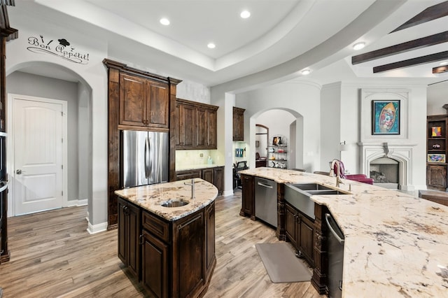 7617 Lazy River Cv, Austin, TX 78730 - kitchen featuring stainless steel appliances, a sink, arched walkways, recessed lighting, and light stone countertops