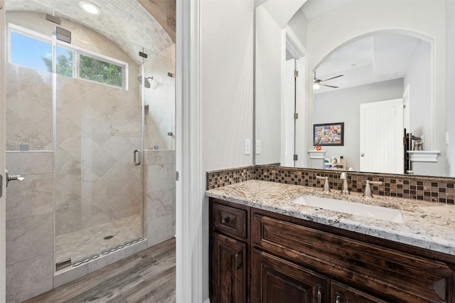 7617 Lazy River Cv, Austin, TX 78730 - bathroom featuring vanity, a ceiling fan, wood finished floors, a shower stall, and decorative backsplash