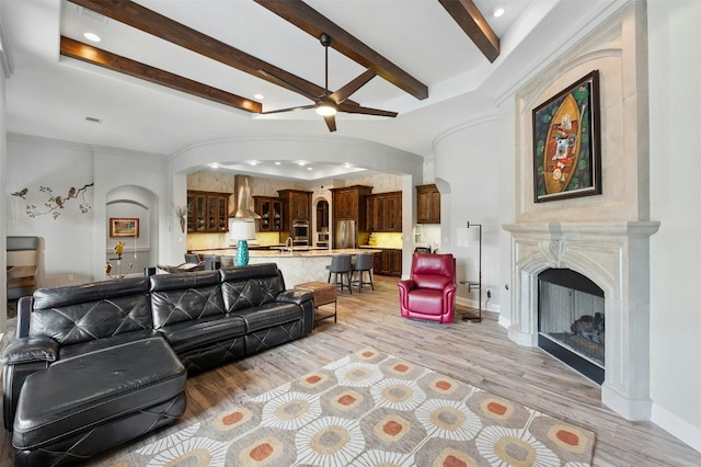 7617 Lazy River Cv, Austin, TX 78730 - living area featuring arched walkways, a ceiling fan, light wood-type flooring, beamed ceiling, and a fireplace