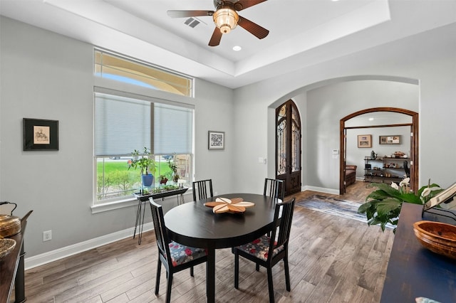 7617 Lazy River Cv, Austin, TX 78730 - dining area featuring arched walkways, a raised ceiling, ceiling fan, light wood-type flooring, and baseboards
