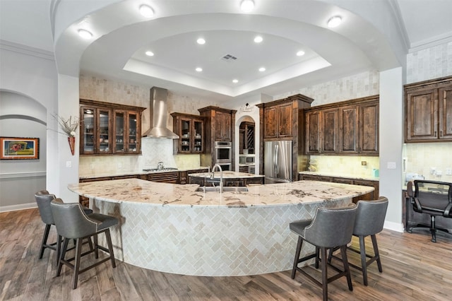 7617 Lazy River Cv, Austin, TX 78730 - kitchen with wall chimney range hood, appliances with stainless steel finishes, a sink, a large island, and recessed lighting