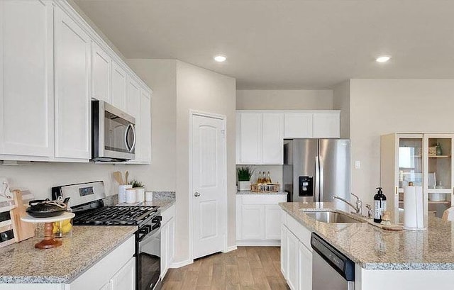 188 Grey Slate Ave, Marble Falls, TX 78654 - kitchen with appliances with stainless steel finishes, a sink, a kitchen island with sink, light wood-type flooring, and white cabinets