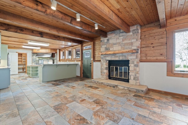 180 Bradley Ln, Rosanky, TX 78953 - unfurnished living room featuring a stone fireplace, a wooden ceiling with exposed beams, rail lighting, and stone tile floors