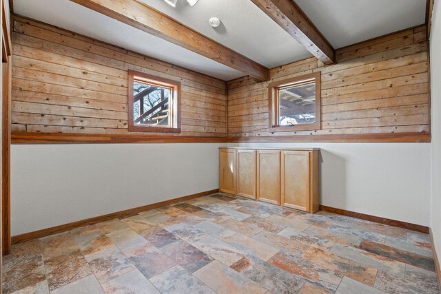 180 Bradley Ln, Rosanky, TX 78953 - spare room with beam ceiling, wooden walls, and light stone finish floors