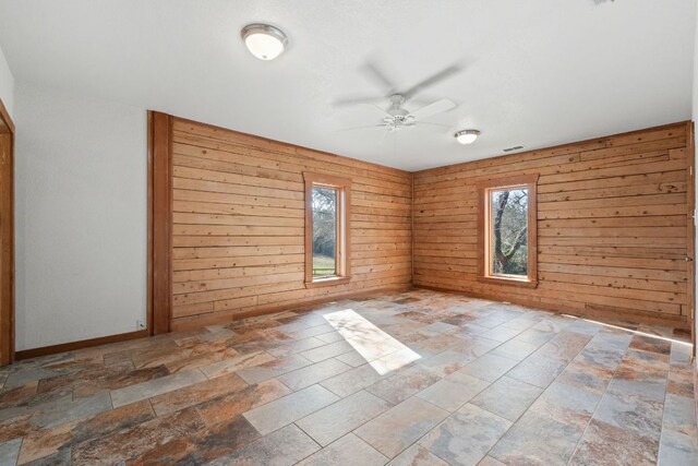 180 Bradley Ln, Rosanky, TX 78953 - unfurnished room featuring a ceiling fan, stone tile floors, plenty of natural light, and wood walls