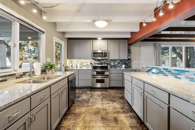 421 Yucca Dr, Kingsland, TX 78639 - kitchen featuring gray cabinetry, appliances with stainless steel finishes, backsplash, beam ceiling, and light stone counters