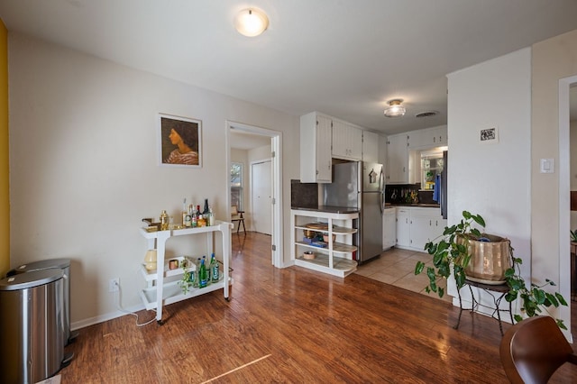 4701 Sylvandale Dr Unit 1, Austin, TX 78745 - kitchen with freestanding refrigerator, white cabinetry, dark countertops, and light wood-type flooring
