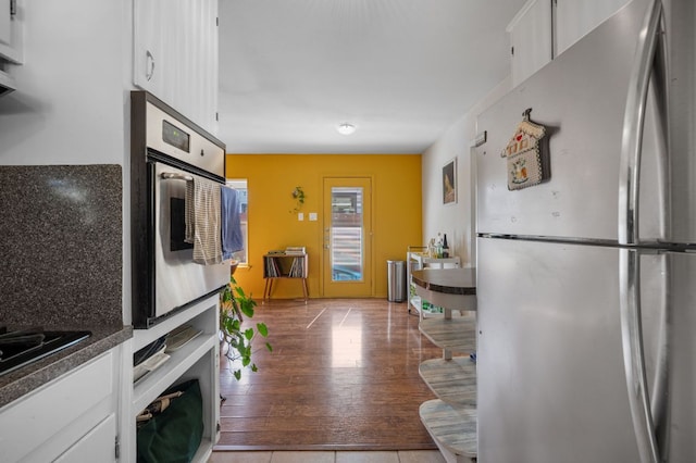 4701 Sylvandale Dr Unit 1, Austin, TX 78745 - kitchen with freestanding refrigerator, stainless steel oven, white cabinetry, and dark countertops