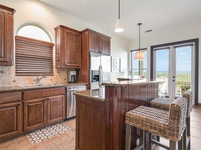 17545 E Reed Parks Rd Unit 5, Jonestown, TX 78645 - kitchen with appliances with stainless steel finishes, a sink, decorative backsplash, a kitchen island, and dark stone countertops