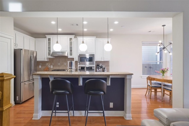 6305 Carrington Dr, Austin, TX 78749 - kitchen featuring stainless steel appliances, under cabinet range hood, tasteful backsplash, light wood finished floors, and recessed lighting