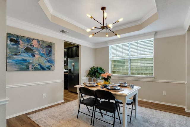 606 Indian Run Dr, Pflugerville, TX 78660 - dining room featuring a tray ceiling, a chandelier, wood finished floors, crown molding, and baseboards