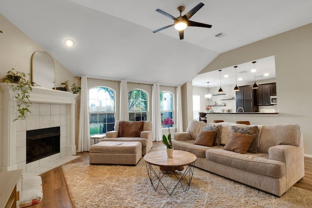 606 Indian Run Dr, Pflugerville, TX 78660 - living area with wood finished floors, vaulted ceiling, a ceiling fan, a tile fireplace, and plenty of natural light