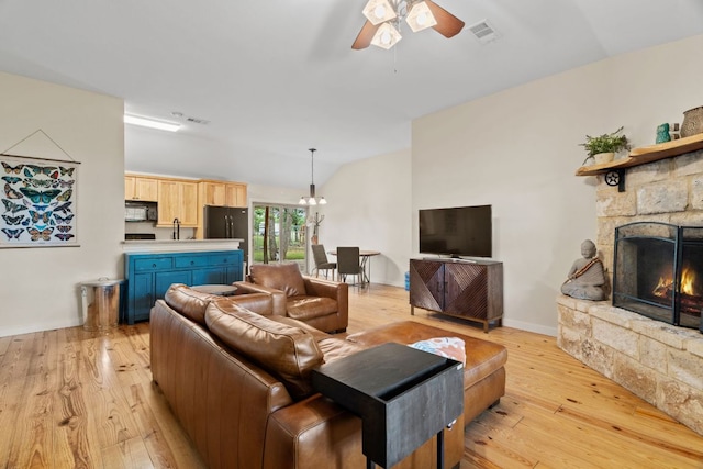 3434 Prairie Lea Rd, Kingsbury, TX 78638 - living room featuring vaulted ceiling, light wood finished floors, a ceiling fan, a fireplace, and a chandelier