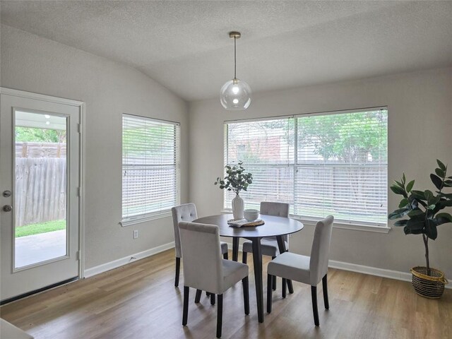 9403 Tea Rose Trl, Austin, TX 78748 - dining area featuring wood finished floors, vaulted ceiling, baseboards, and a textured ceiling