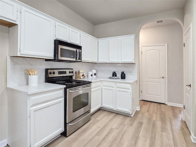 9403 Tea Rose Trl, Austin, TX 78748 - kitchen with stainless steel appliances, light wood finished floors, tasteful backsplash, arched walkways, and white cabinetry
