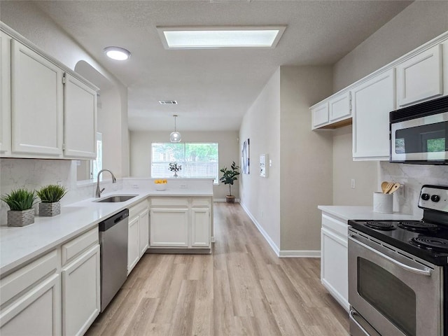 9403 Tea Rose Trl, Austin, TX 78748 - kitchen featuring stainless steel appliances, a sink, light wood-style floors, a peninsula, and white cabinetry