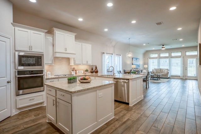 108 Berkeley Pl, Georgetown, TX 78628 - kitchen with appliances with stainless steel finishes, a sink, a kitchen island, a peninsula, and dark wood-type flooring