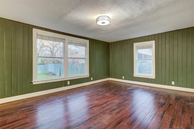 1309 E 13th St, Austin, TX 78702 - empty room featuring hardwood / wood-style flooring, a textured ceiling, baseboards, and wood walls