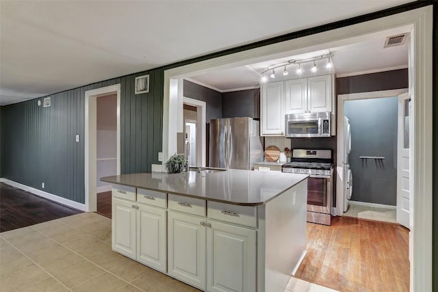 1309 E 13th St, Austin, TX 78702 - kitchen featuring appliances with stainless steel finishes, light wood-style flooring, white cabinetry, baseboards, and ornamental molding