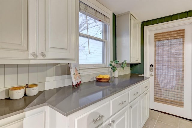 1309 E 13th St, Austin, TX 78702 - kitchen featuring backsplash, white cabinets, light tile patterned floors, and dark countertops