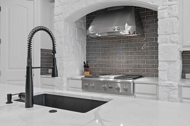 7609 Lazy River Cv, Austin, TX 78730 - kitchen featuring wall chimney exhaust hood, stove, white cabinets, and tasteful backsplash