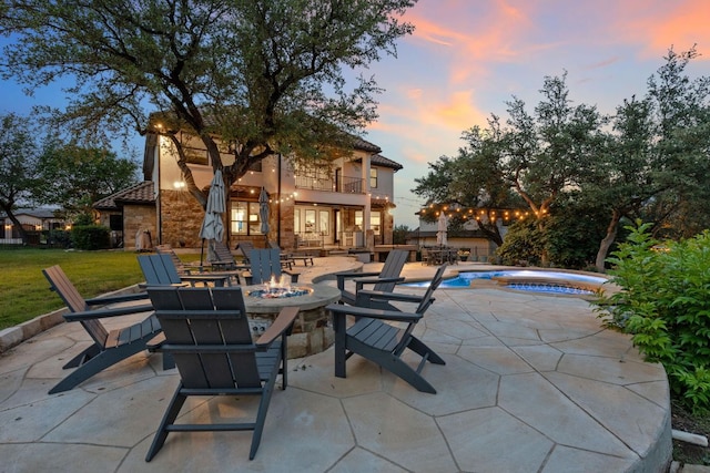 7609 Lazy River Cv, Austin, TX 78730 - patio terrace at dusk with a balcony, a fire pit, a hot tub, a patio area, and an outdoor pool