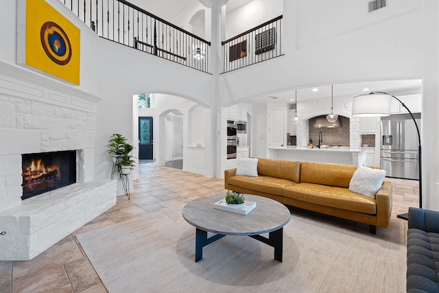 7609 Lazy River Cv, Austin, TX 78730 - living room with arched walkways, a fireplace, stone tile floors, and a towering ceiling