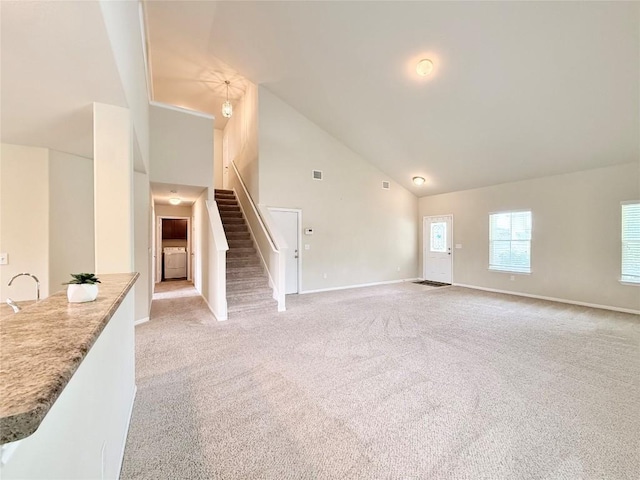 110 Carbine Ct, Bastrop, TX 78602 - unfurnished living room featuring light carpet, stairway, high vaulted ceiling, baseboards, and a sink