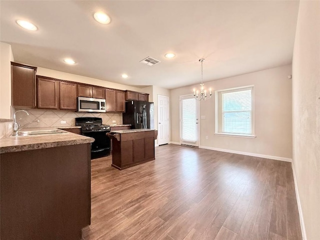 110 Carbine Ct, Bastrop, TX 78602 - kitchen featuring range with gas cooktop, stainless steel microwave, black refrigerator with ice dispenser, a sink, and a center island