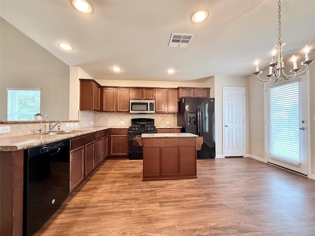 110 Carbine Ct, Bastrop, TX 78602 - kitchen featuring black appliances, a sink, a chandelier, tasteful backsplash, and light wood finished floors