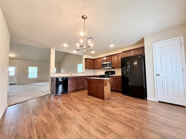 110 Carbine Ct, Bastrop, TX 78602 - kitchen with black appliances, a chandelier, open floor plan, light wood finished floors, and a center island