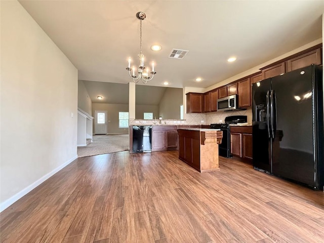 110 Carbine Ct, Bastrop, TX 78602 - kitchen featuring black appliances, a chandelier, open floor plan, wood finished floors, and a center island