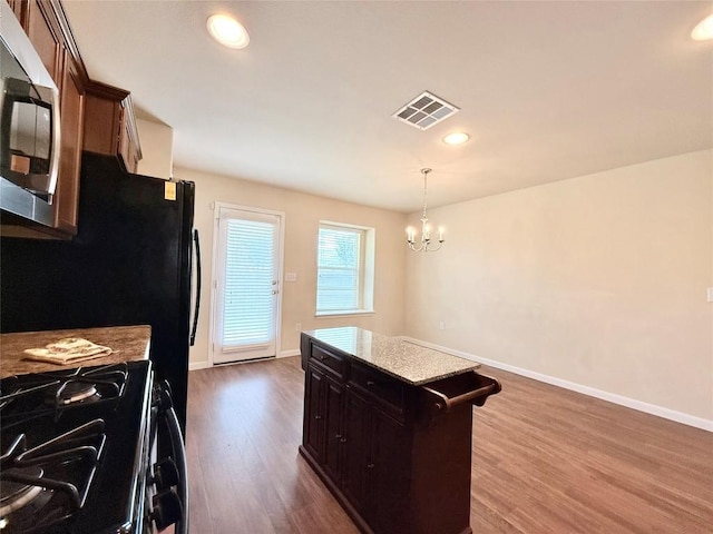 110 Carbine Ct, Bastrop, TX 78602 - kitchen featuring gas stove, stainless steel microwave, dark wood-type flooring, a chandelier, and baseboards