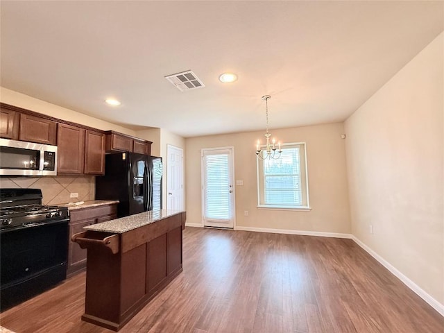 110 Carbine Ct, Bastrop, TX 78602 - kitchen featuring black appliances, a chandelier, dark wood-type flooring, tasteful backsplash, and baseboards