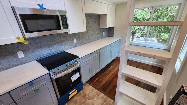 1134 Lott Ave, Austin, TX 78721 - kitchen with stainless steel microwave, range with electric stovetop, tasteful backsplash, white cabinetry, and dark wood-type flooring