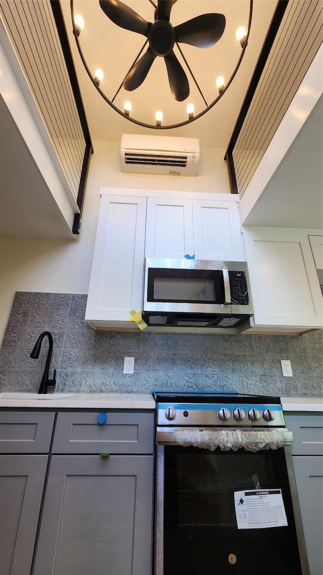 1134 Lott Ave, Austin, TX 78721 - kitchen featuring stainless steel appliances, gray cabinets, light countertops, and a wall mounted air conditioner