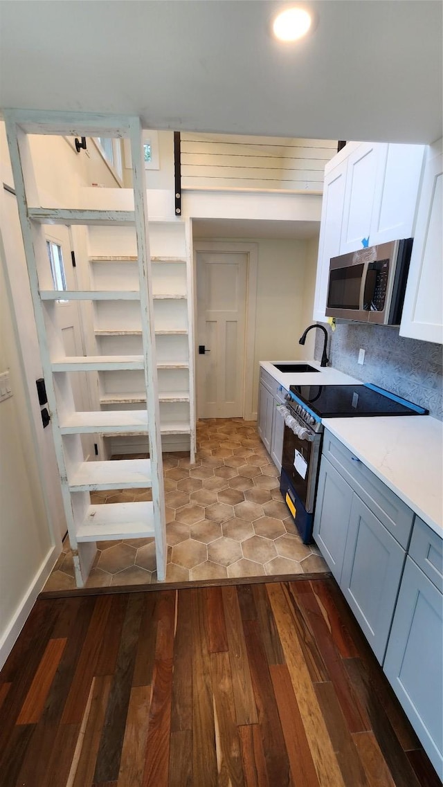 1134 Lott Ave, Austin, TX 78721 - kitchen featuring stainless steel microwave, range with electric stovetop, a sink, light countertops, and wood finished floors