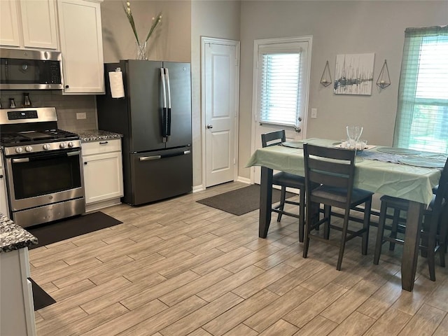 520 Warlander Way, Georgetown, TX 78626 - kitchen featuring stainless steel appliances, light wood-style flooring, decorative backsplash, white cabinetry, and dark stone countertops