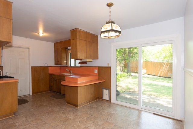 6903 N La Salle Dr, Austin, TX 78723 - kitchen with a peninsula, brown cabinetry, decorative light fixtures, a sink, and light countertops