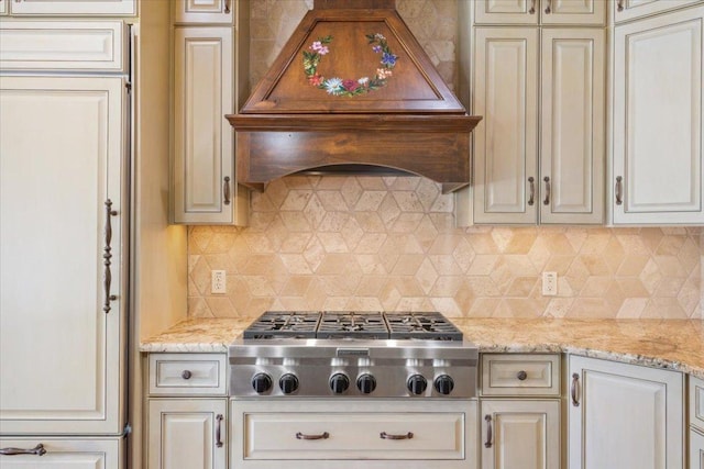 1111 Mill Creek Dr, Salado, TX 76571 - kitchen with stainless steel gas stovetop, custom exhaust hood, backsplash, cream cabinetry, and light stone counters