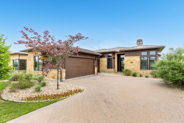 2317 Kahala Sunset Dr, Spicewood, TX 78669 - view of front of property with a standing seam roof, stone siding, a garage, decorative driveway, and a chimney