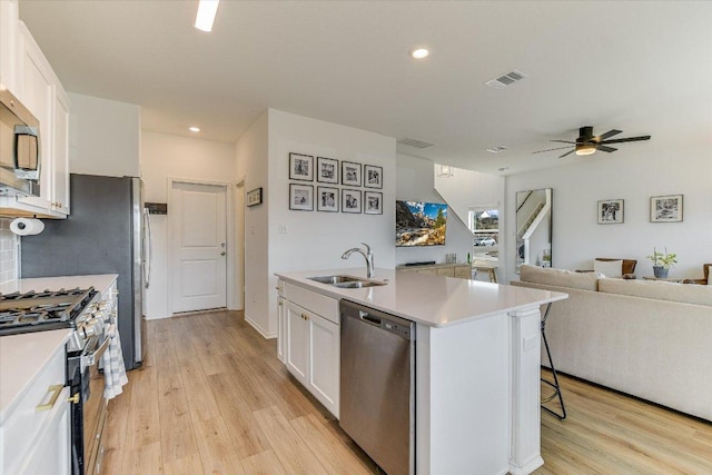 101 Wind Flower Ln, Liberty Hill, TX 78642 - kitchen with appliances with stainless steel finishes, white cabinets, open floor plan, light wood-type flooring, and recessed lighting
