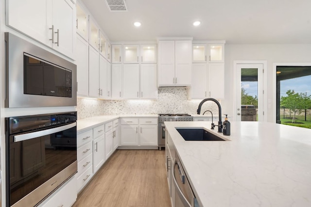 504 Tomichi Trl, Austin, TX 78738 - kitchen with appliances with stainless steel finishes, a sink, white cabinets, light wood-style flooring, and light stone countertops