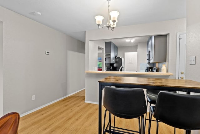 806 W 24th St Unit 302, Austin, TX 78705 - kitchen featuring a chandelier, light wood-style flooring, freestanding refrigerator, gray cabinetry, and baseboards